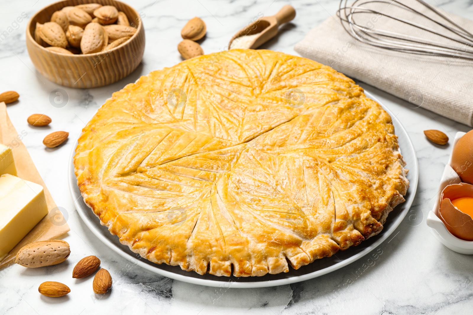 Photo of Traditional galette des rois and ingredients on white marble table