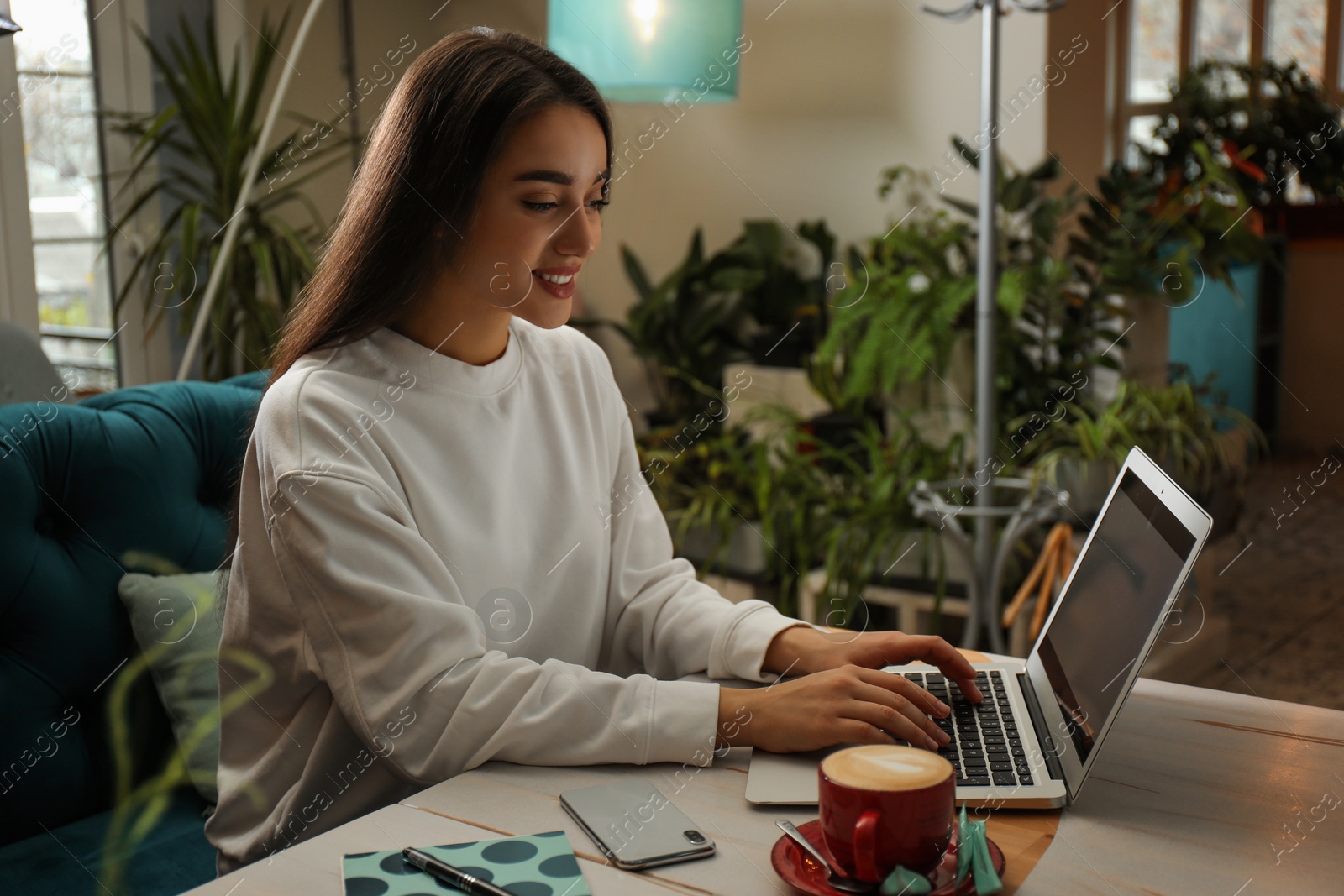 Photo of Young blogger working with laptop in cafe