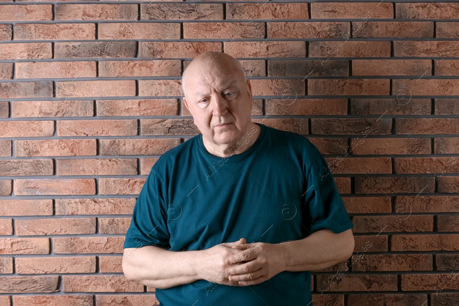 Photo of Senior man in state of depression near brick wall