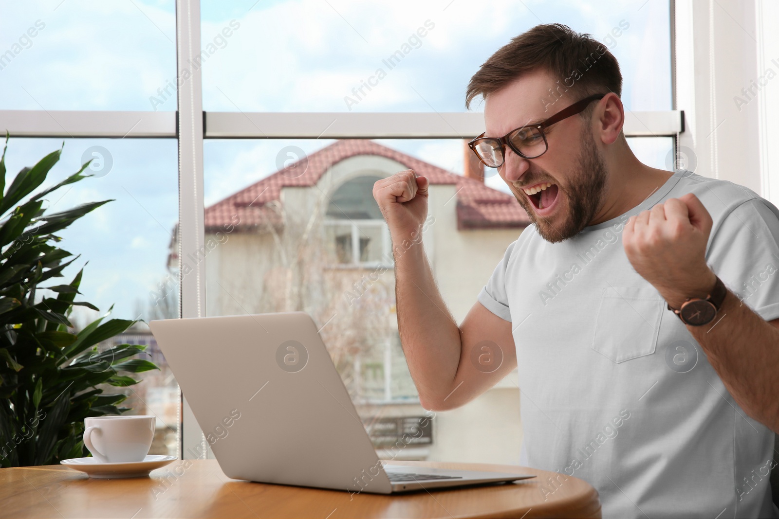 Photo of Emotional man participating in online auction using laptop at home