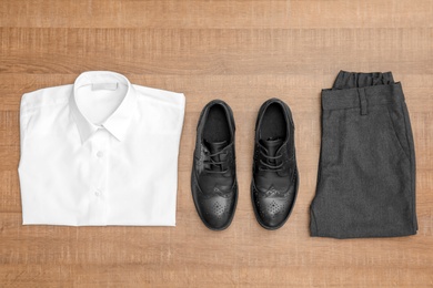 School uniform for boy on wooden background, top view