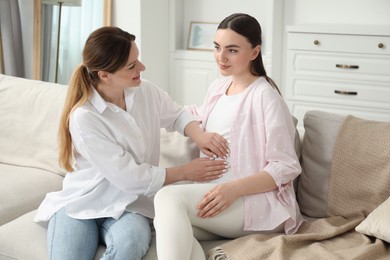 Photo of Doula taking care of pregnant woman on sofa at home. Preparation for child birth