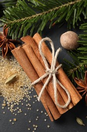 Different spices, nut and fir branches on gray table, flat lay