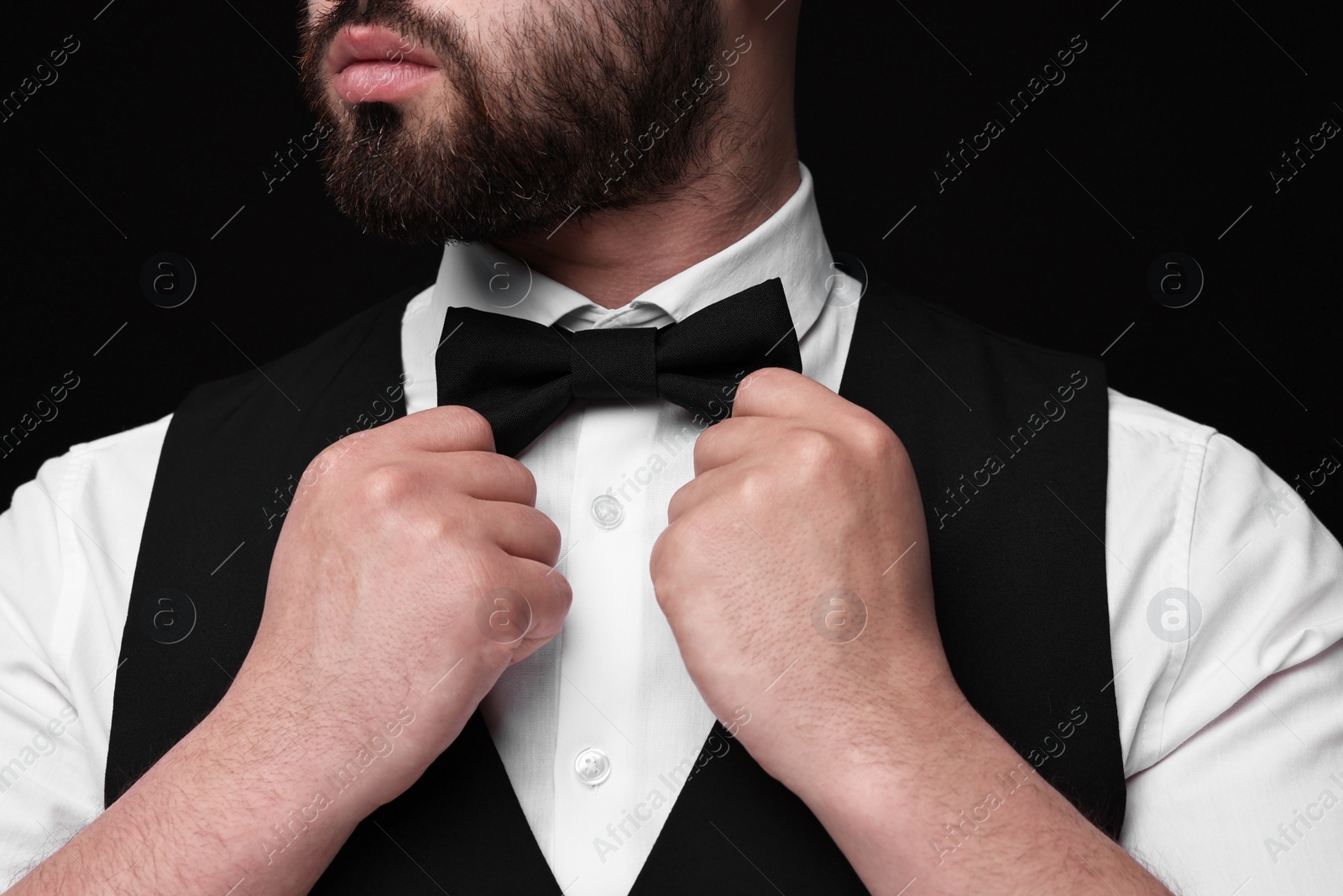 Photo of Man in shirt and bow tie on black background, closeup