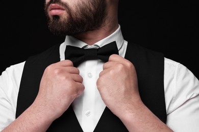 Photo of Man in shirt and bow tie on black background, closeup