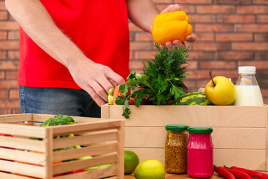 Man with fresh products at table indoors, closeup. Food delivery service