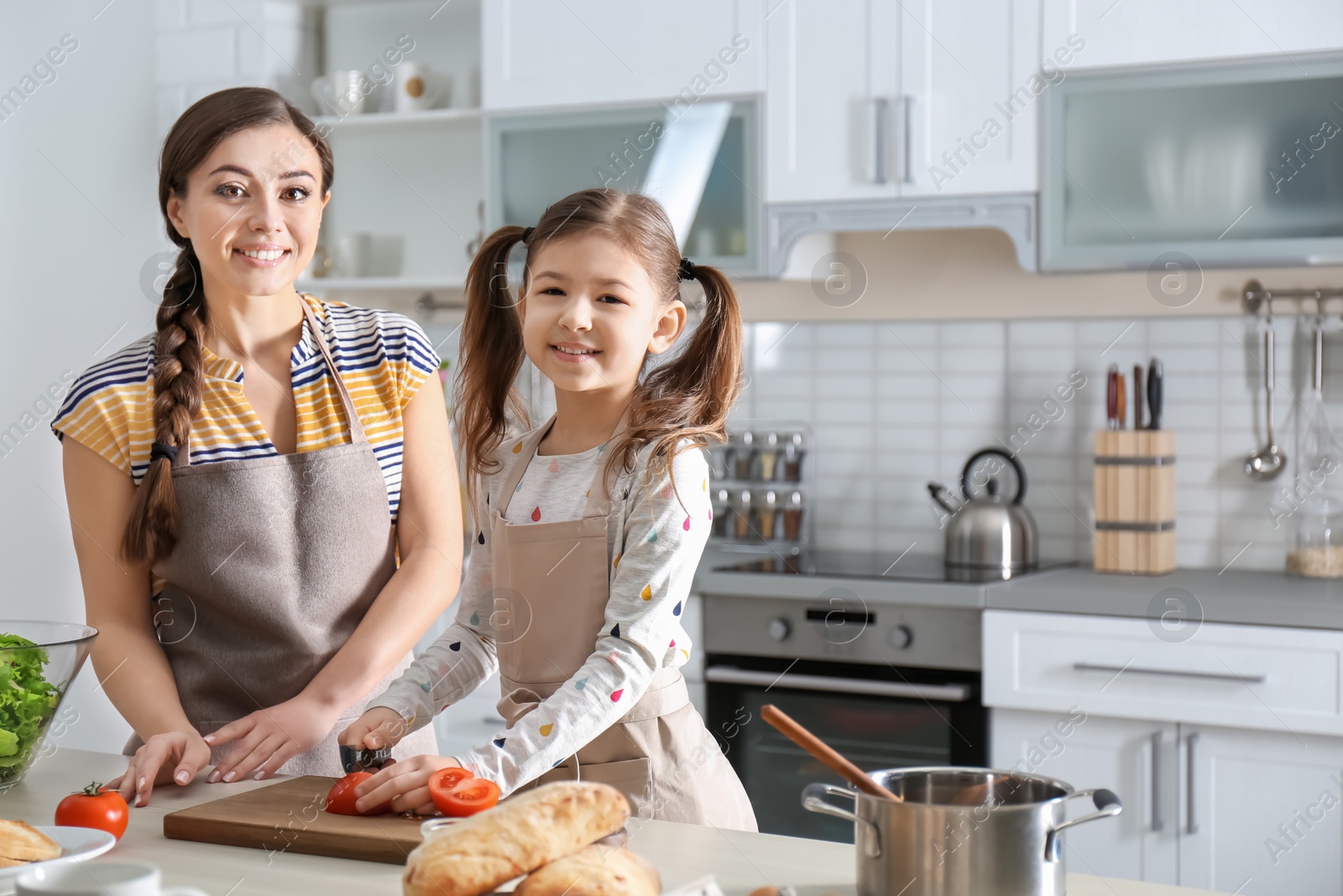 Photo of Young nanny with cute little girl cooking together in kitchen