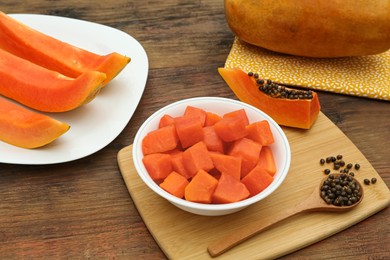 Photo of Tasty cut and whole papaya fruits on wooden table, above view