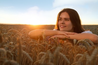 Photo of Beautiful young woman sitting in ripe wheat field at sunset