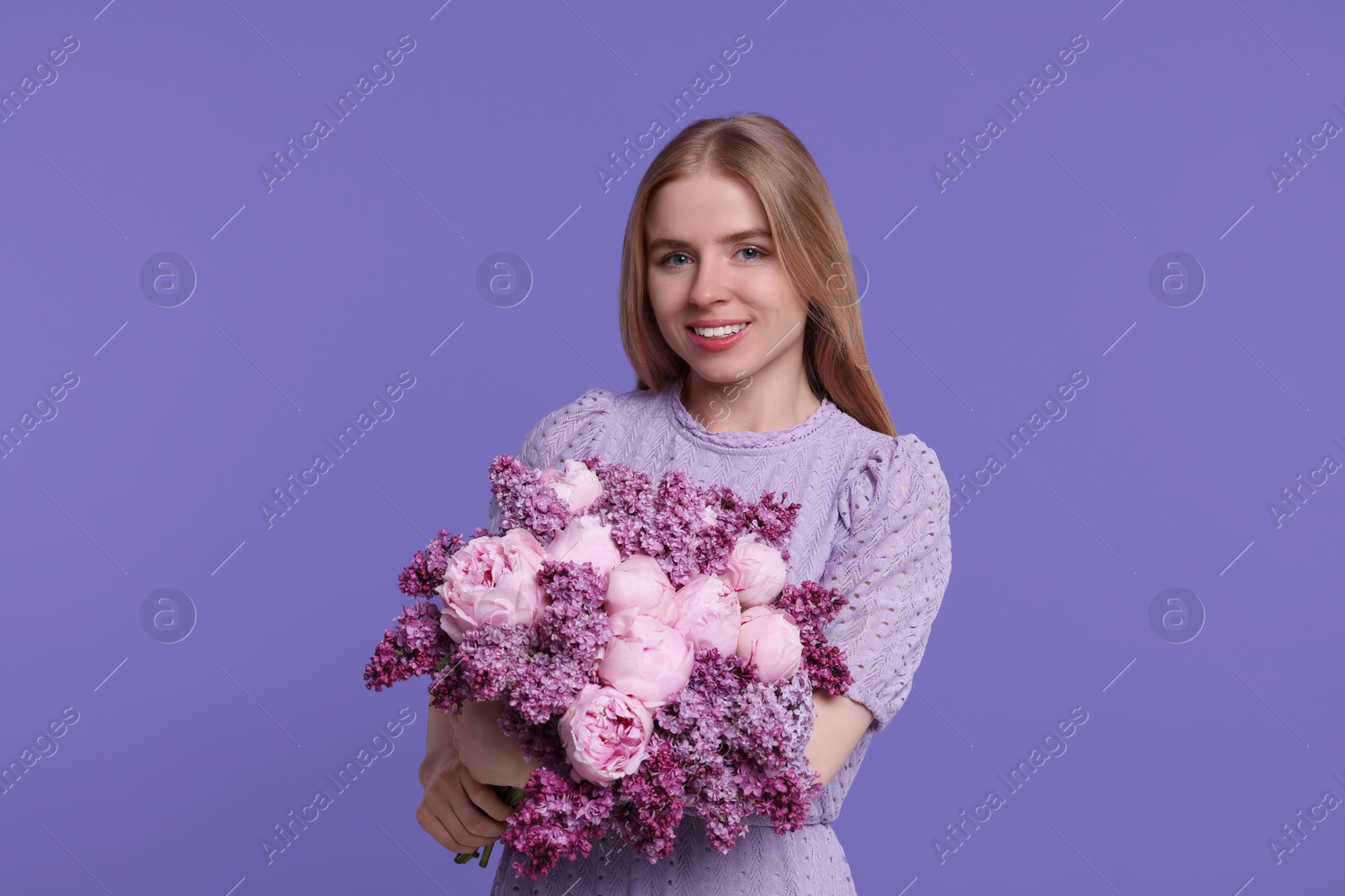 Photo of Beautiful woman with bouquet of spring flowers on purple background