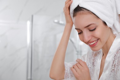 Photo of Beautiful young woman with hair wrapped in towel after washing at home, closeup. Space for text