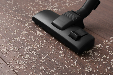 Photo of Vacuuming scattered rice from wooden floor, closeup