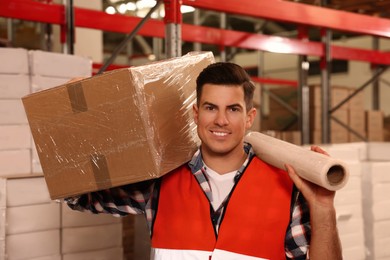 Photo of Worker with roll of stretch film and wrapped box in warehouse