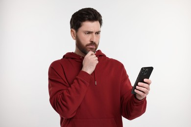 Thoughtful man with smartphone on white background