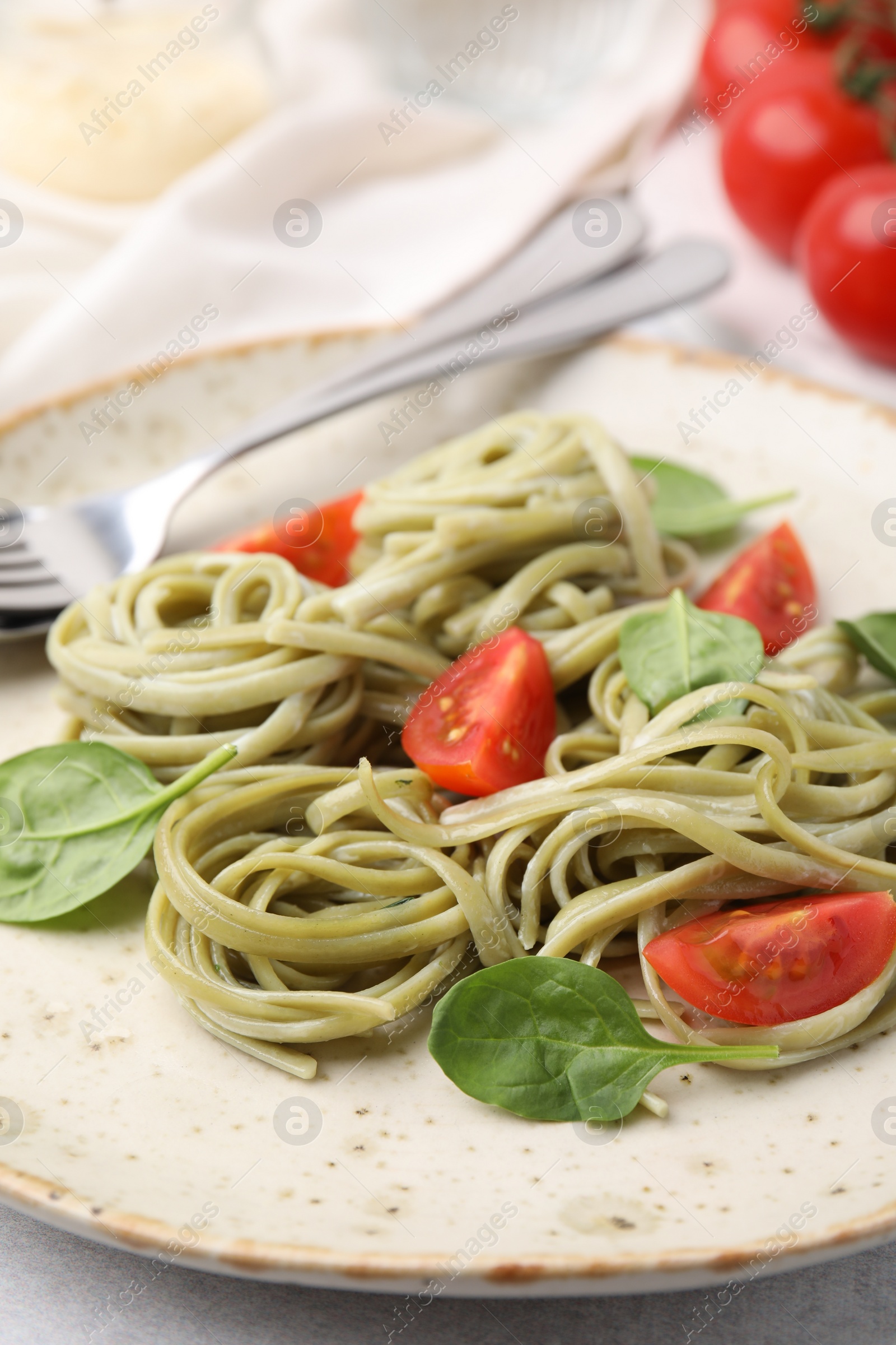 Photo of Tasty pasta with spinach and tomatoes on light table, closeup