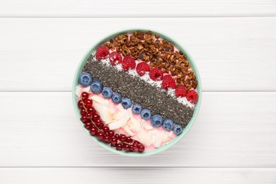 Photo of Tasty smoothie bowl with fresh berries and granola on white wooden table, top view