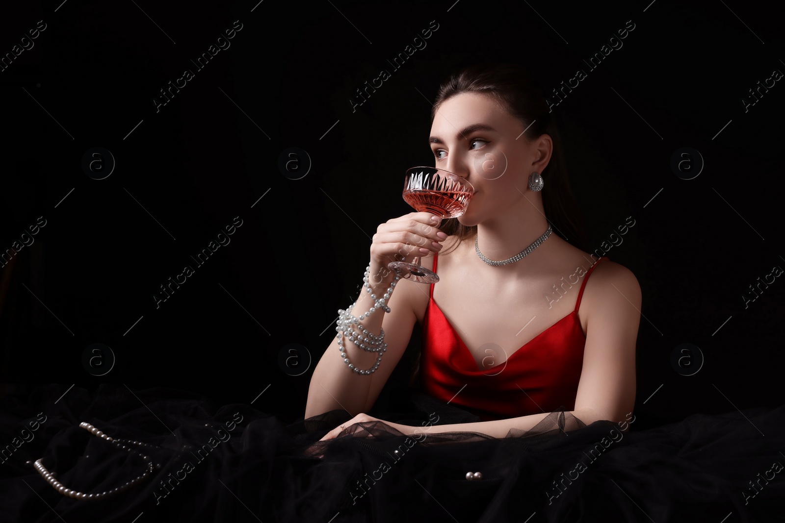 Photo of Fashionable photo of attractive young woman drinking wine on black background