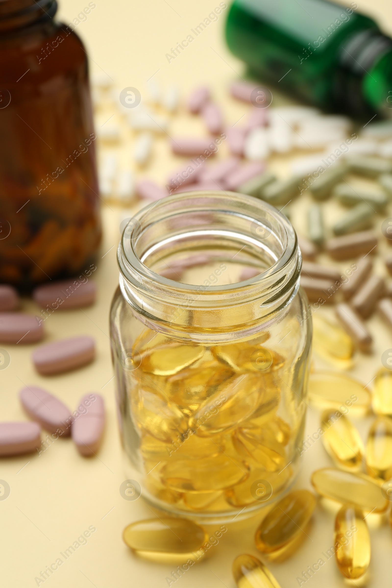 Photo of Many different vitamin pills and bottles on beige background, closeup