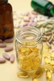 Photo of Many different vitamin pills and bottles on beige background, closeup