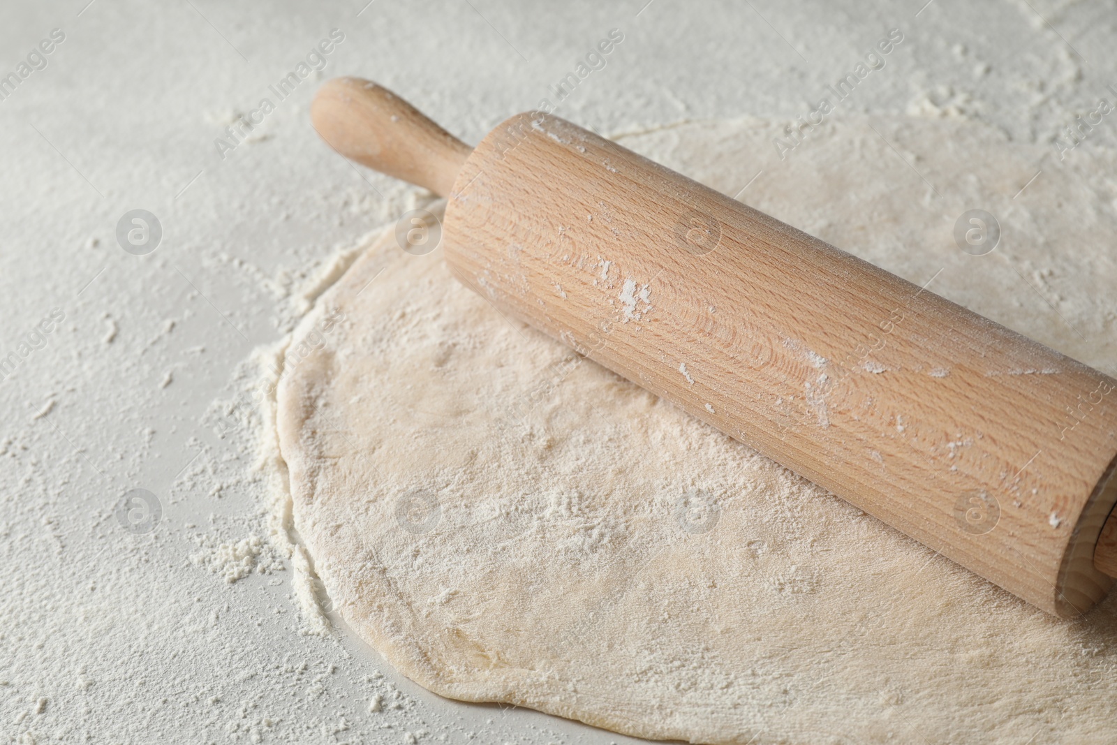 Photo of Raw dough and rolling pin on table