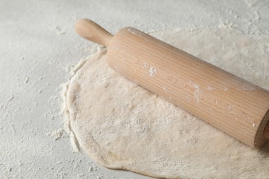 Photo of Raw dough and rolling pin on table