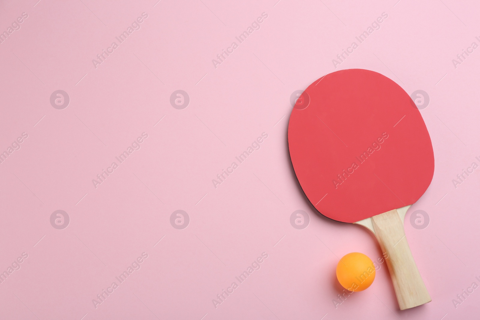 Photo of Ping pong racket and ball on pink background, flat lay. Space for text