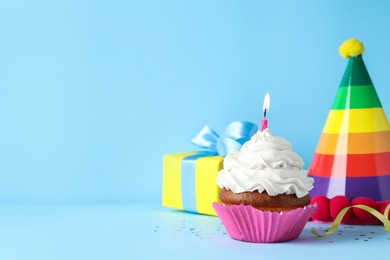 Photo of Delicious birthday cupcake with candle on light blue background, space for text