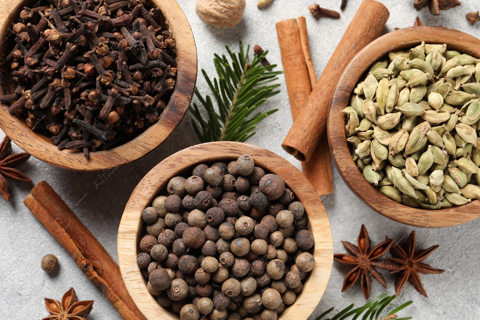 Photo of Different aromatic spices and fir branches on light textured table, flat lay