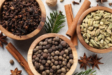 Photo of Different aromatic spices and fir branches on light textured table, flat lay