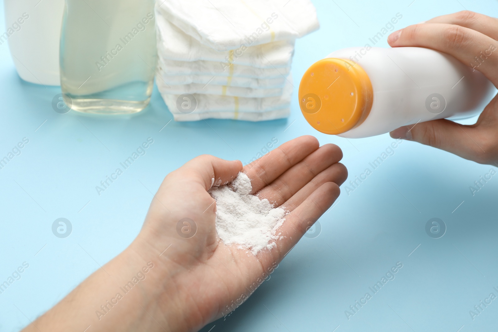 Photo of Woman applying dusting powder on light blue background, top view