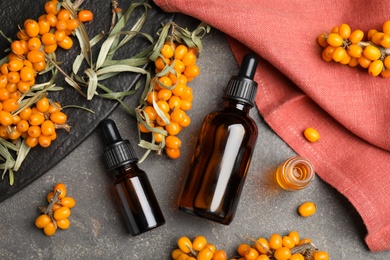 Photo of Flat lay composition with sea buckthorn oil on grey table