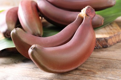 Delicious red baby bananas on wooden table, closeup