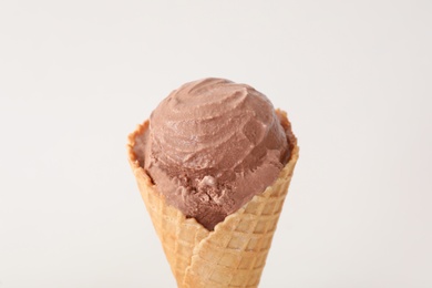Delicious chocolate ice cream in waffle cone on white background, closeup