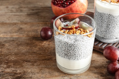 Photo of Tasty chia seed pudding with granola and ingredients on table. Space for text
