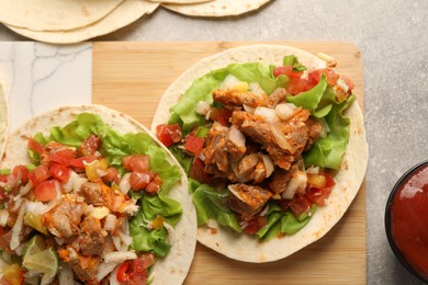 Delicious tacos with vegetables and meat on grey textured table, flat lay