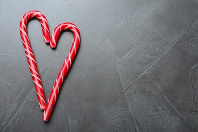 Heart made of Christmas candy canes on grey background, flat lay. Space for text