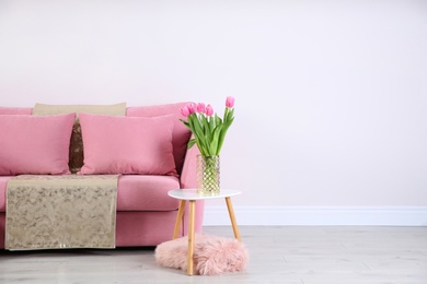 Photo of Stylish pink sofa against white wall in modern living room interior. Space for text