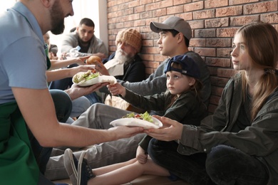 Photo of Volunteers giving food to poor people indoors