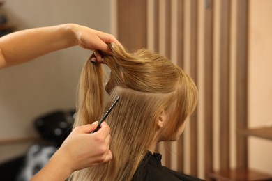 Photo of Professional hairdresser working with girl in beauty salon, closeup