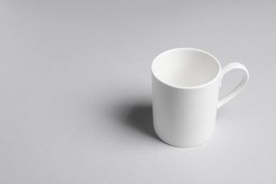 Photo of One white ceramic mug on light background, space for text