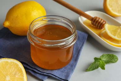 Photo of Sweet honey and fresh lemons on white table, closeup