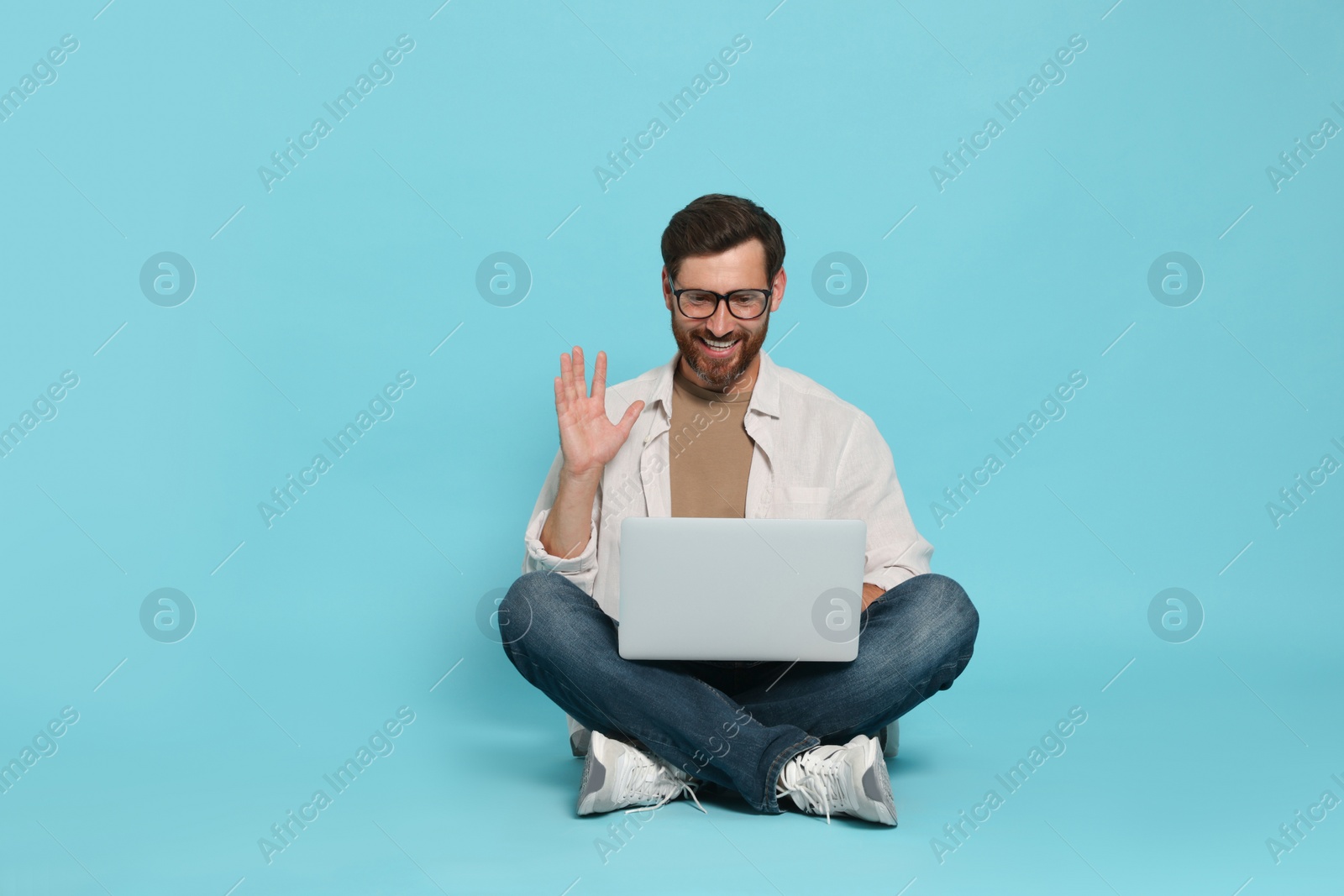 Photo of Handsome man with laptop on light blue background