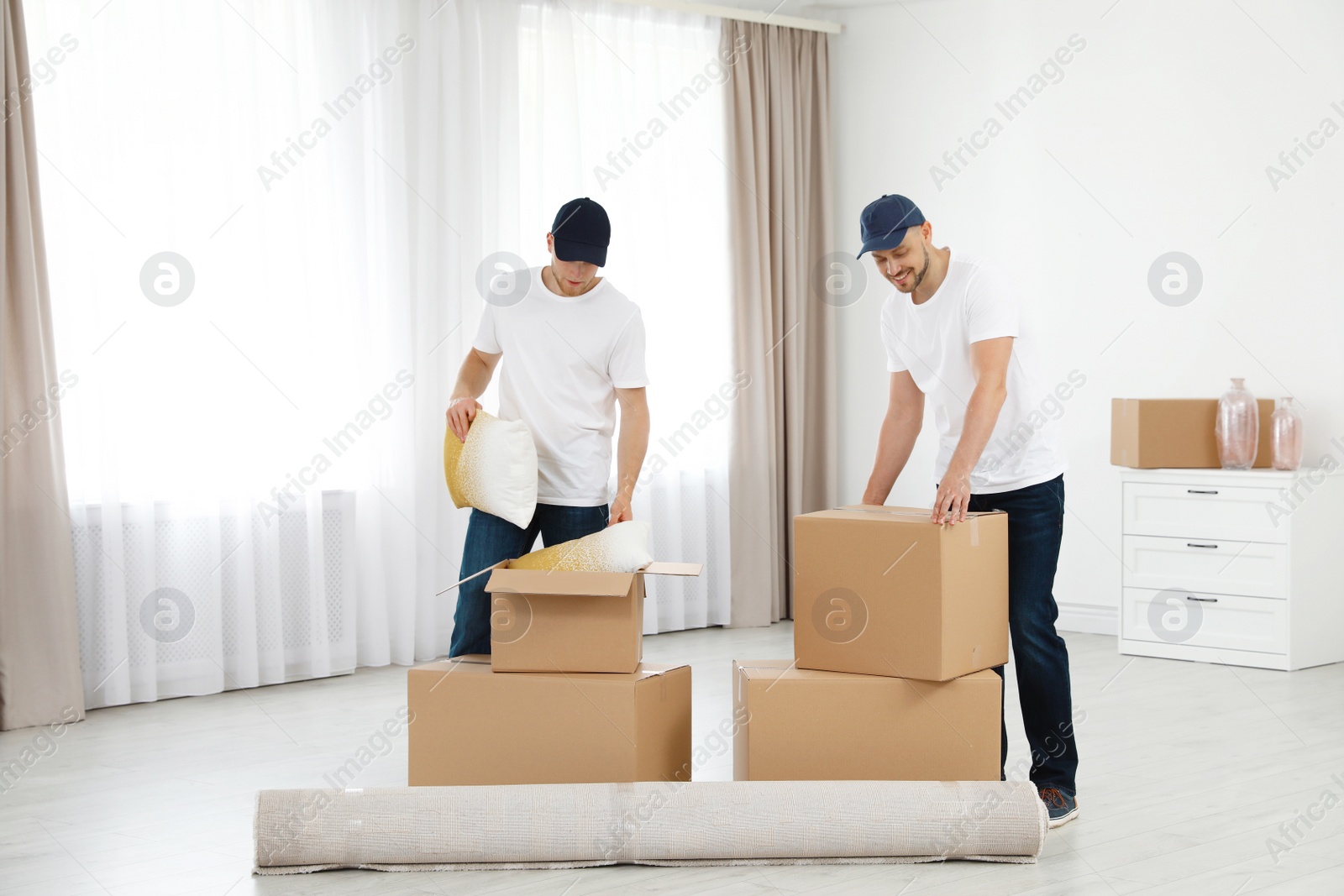 Photo of Moving service employees with cardboard boxes in room