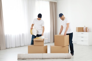 Moving service employees with cardboard boxes in room