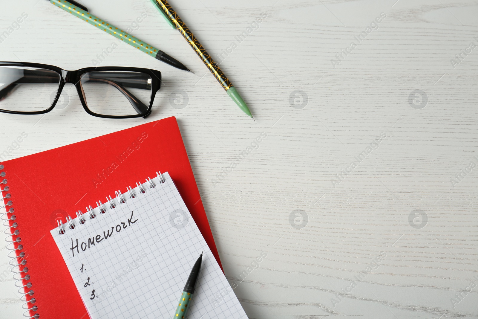 Photo of Flat lay composition of notebook with word HOMEWORK on white wooden table. Space for text