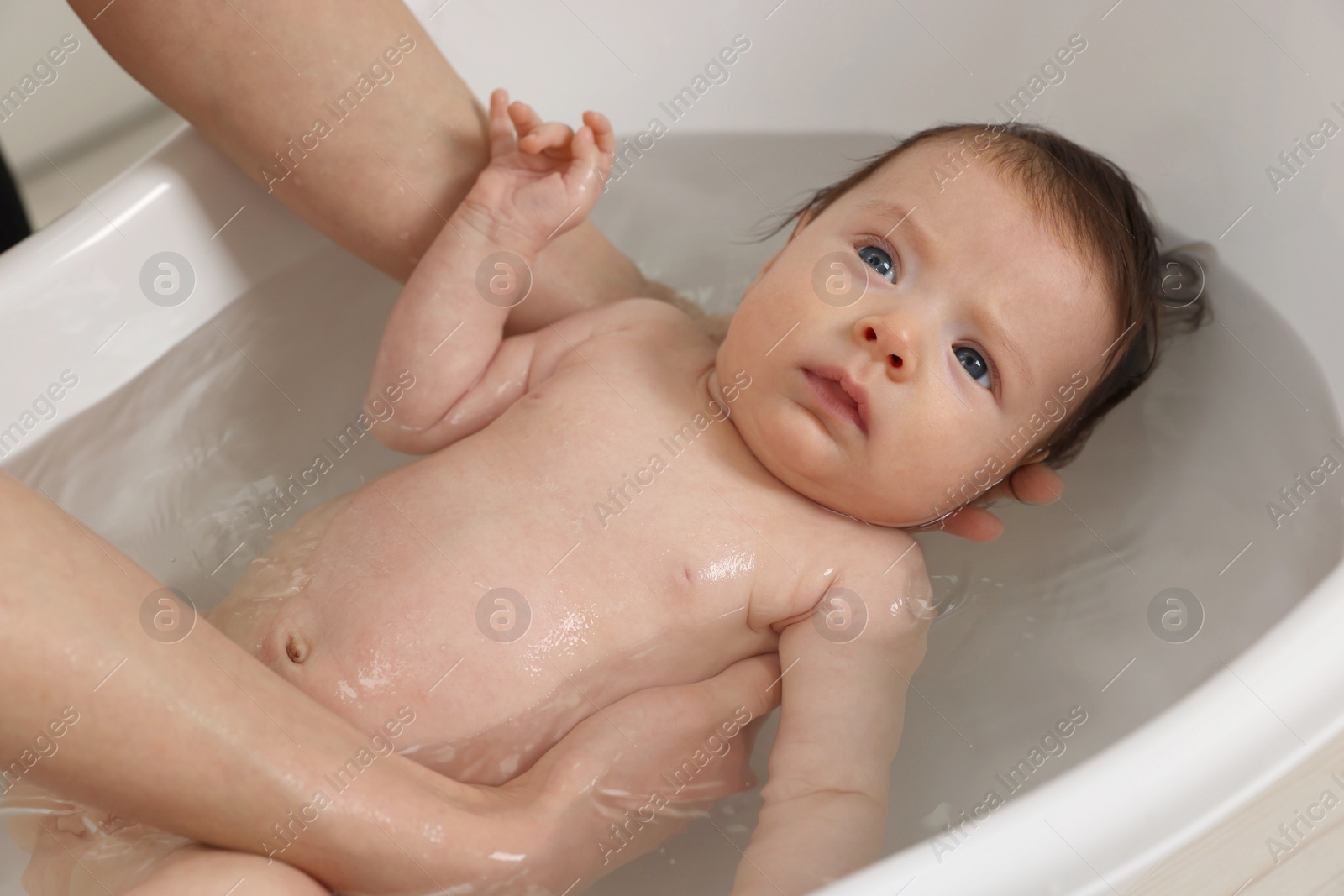 Photo of Mother bathing her little baby in bathtub, closeup