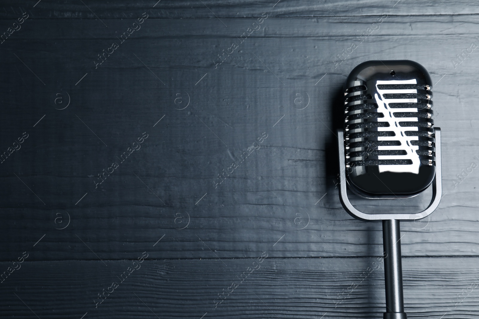 Photo of Retro microphone on wooden background, top view with space for text