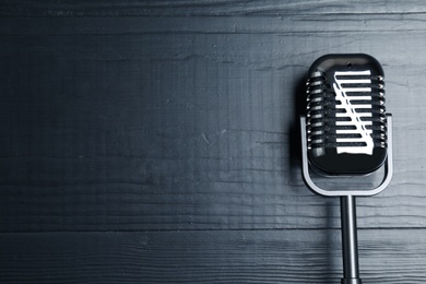 Photo of Retro microphone on wooden background, top view with space for text