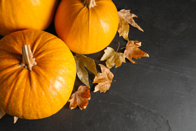 Photo of Ripe pumpkins and autumn leaves on black table, above view