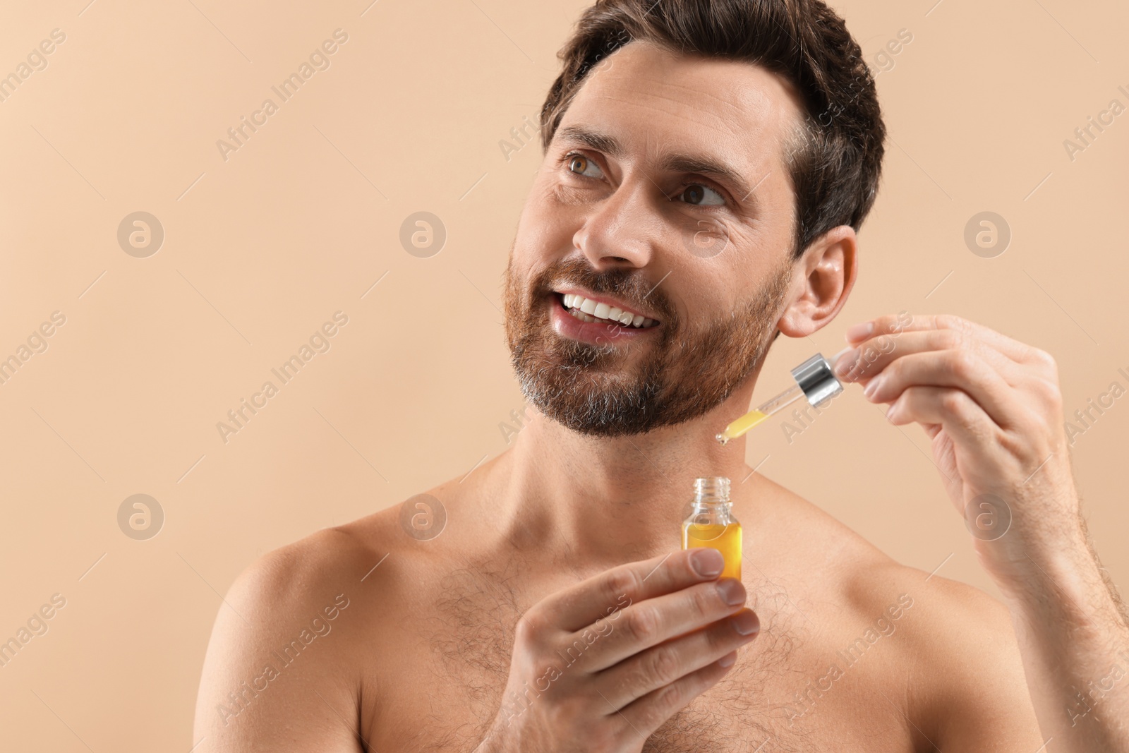 Photo of Handsome man with cosmetic serum on beige background, closeup. Space for text